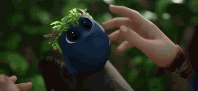 a person is petting a blue monster with horns and a green mane