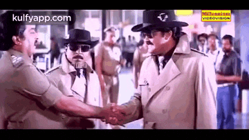 a man in a trench coat and cowboy hat is shaking hands with another man .