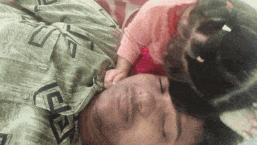 a man laying on a bed with a baby on his chest and a shirt that says ' abercrombie & fitch '