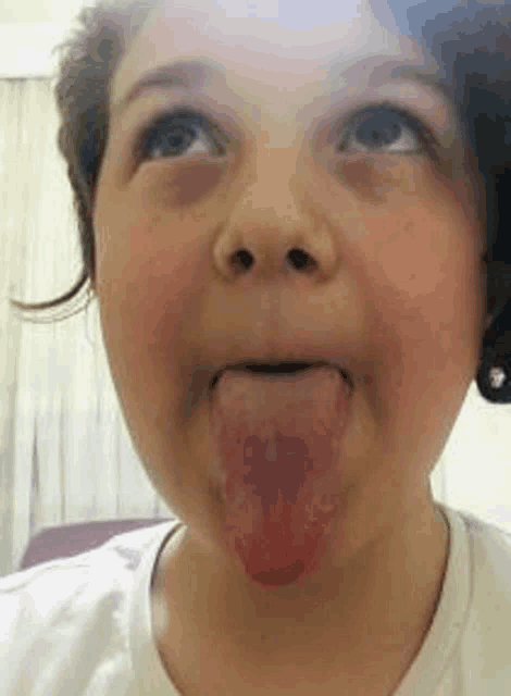 a young girl is sticking her tongue out while making a funny face .