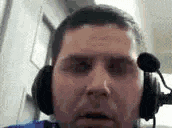 a man wearing headphones and a microphone is making a face .