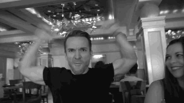 a man in a black shirt is flexing his muscles in a restaurant
