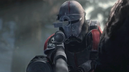 a soldier in a helmet is holding a gun and pointing it at another person .