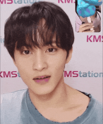 a close up of a person 's face in front of a kms sign
