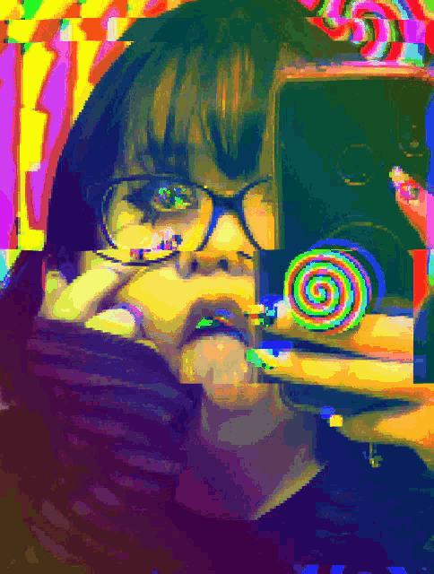 a girl with glasses is holding a colorful lollipop