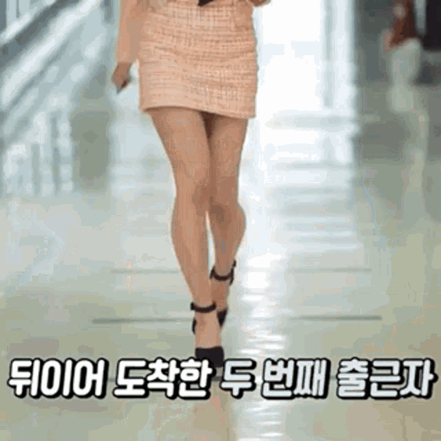 a woman is walking down a hallway wearing a short skirt and high heels .