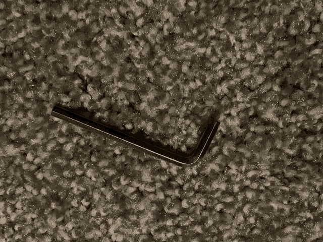 a small wrench is laying on a carpeted surface