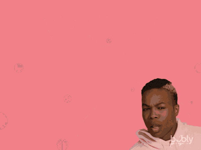 a man in a pink hoodie is standing in front of a pink background with the word wow on it