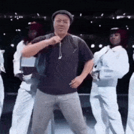 a man is dancing on a stage with a group of women .