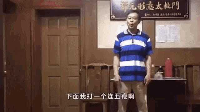 a man in a blue and white striped shirt stands in a room with chinese writing on the wall behind him