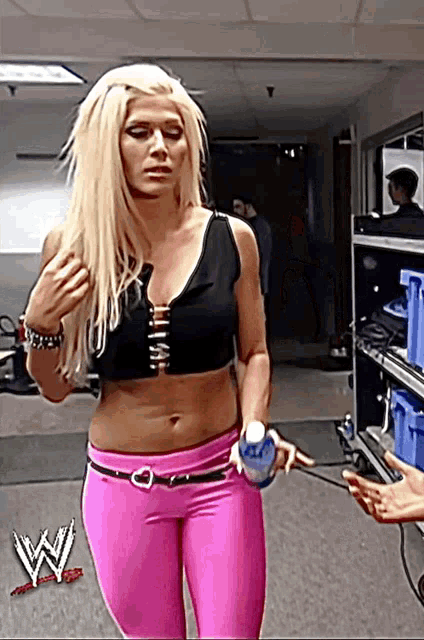 a woman in a black top and pink pants holds a water bottle