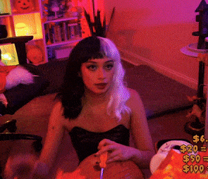 a woman is cutting a pumpkin with a knife in front of a sign that says $ 20 $ 50 and $ 100
