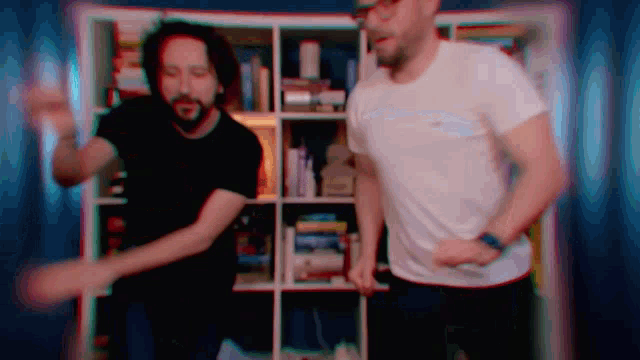 two men dancing in front of a bookshelf with books on it