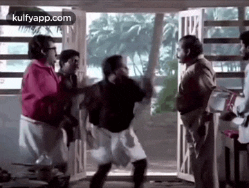 a group of men are standing in front of a door and talking to each other .