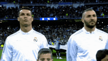 two soccer players stand in front of a crowd wearing white jerseys