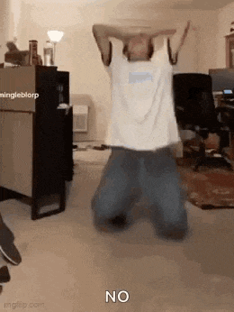 a man is kneeling down in a room with his arms in the air and the word no on the floor .