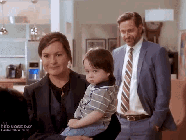 a man in a suit and tie holds a little boy while a woman holds a baby
