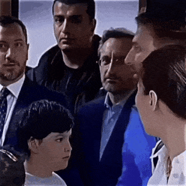 a group of people are standing around a boy in a white shirt .