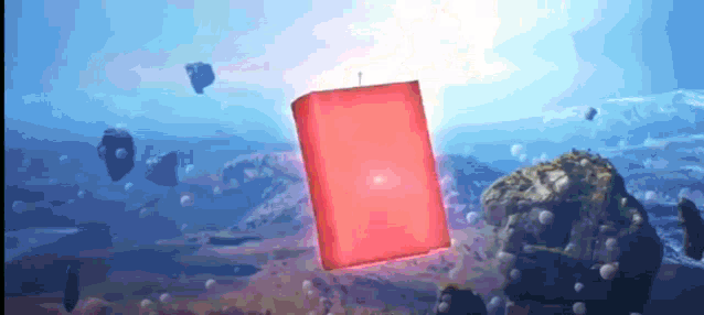 a red cube is floating in the air above a rocky area
