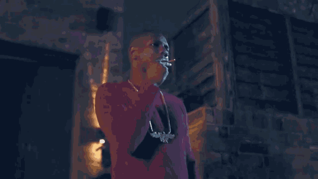 a man in a red sweater is smoking a cigarette outside