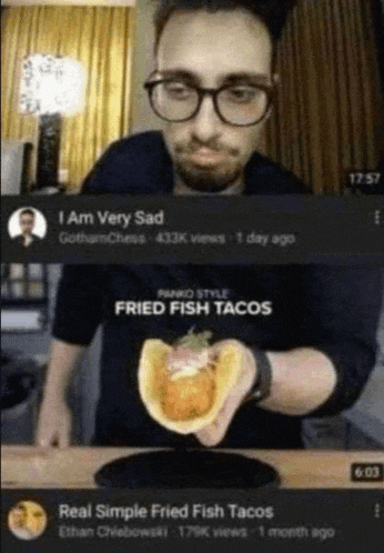 a man with glasses is holding a fried fish taco in his hand