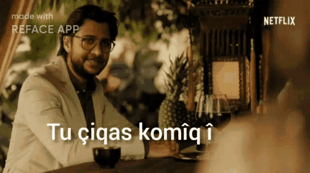 a man is sitting at a table with the words tu ciqas komiq i on the bottom