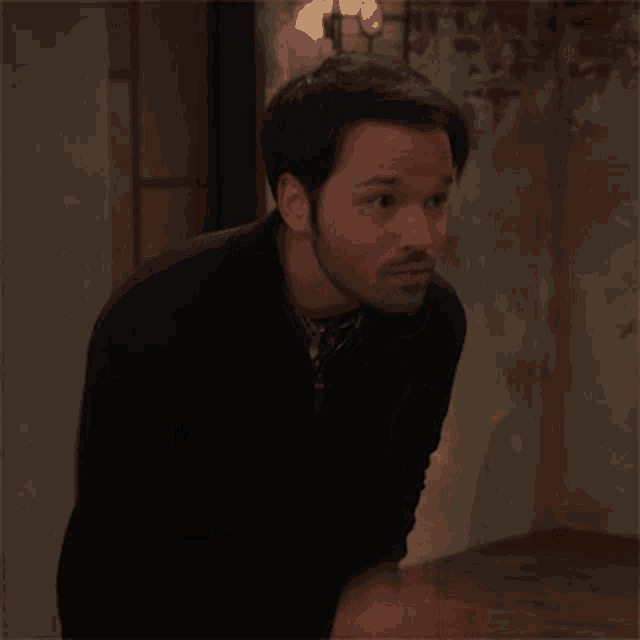 a man with a beard is standing in a room looking at something .