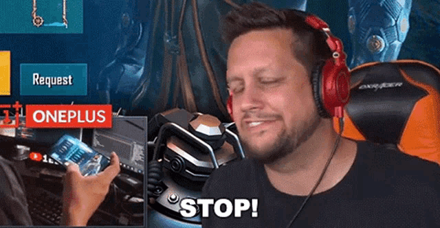 a man wearing red headphones is sitting in front of a oneplus sign