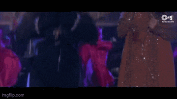 a man is dancing in front of a woman in a pink dress in a club .