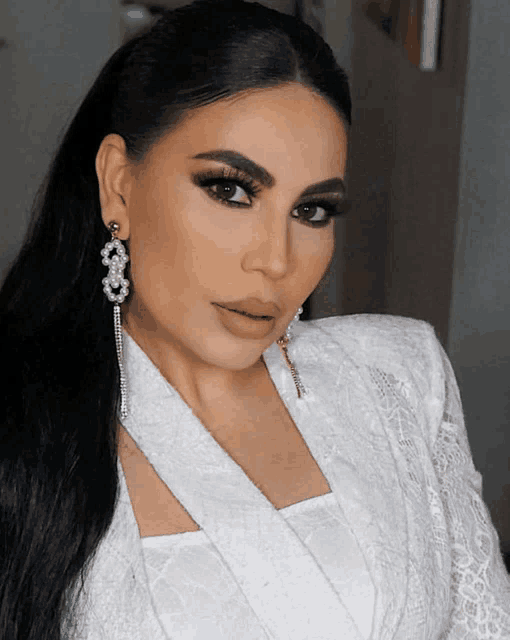 a woman wearing a white jacket and earrings with the number 3