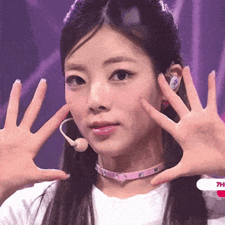 a woman wearing a choker and ear buds is making a face with her hands