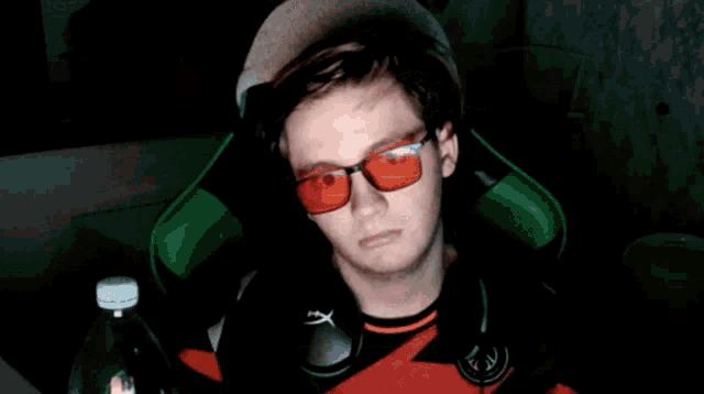 a man with red spots on his face is sitting in a chair holding a bottle