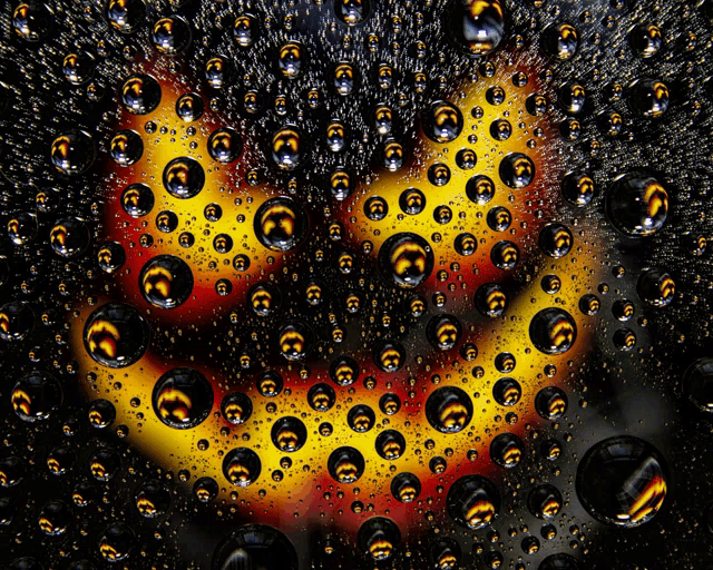 a smiley face is surrounded by water drops on a black surface