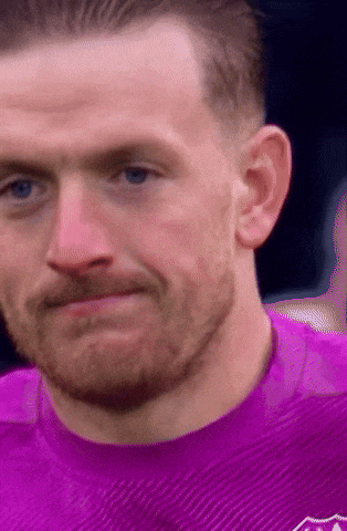 a close up of a man 's face with a purple shirt on