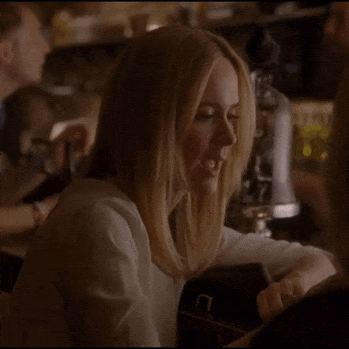 a woman in a white shirt is drinking a glass of wine
