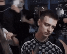 a young man is sitting in a crowd of people in a dark room .