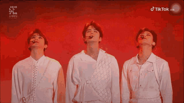 three men in white shirts are standing in front of a red background that says tiktok on the bottom