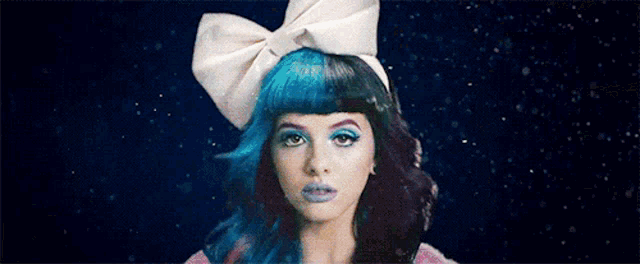 a woman with blue and black hair is wearing a white bow on her head .