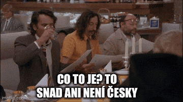 a group of men are sitting at a table and one of them is drinking a glass of water