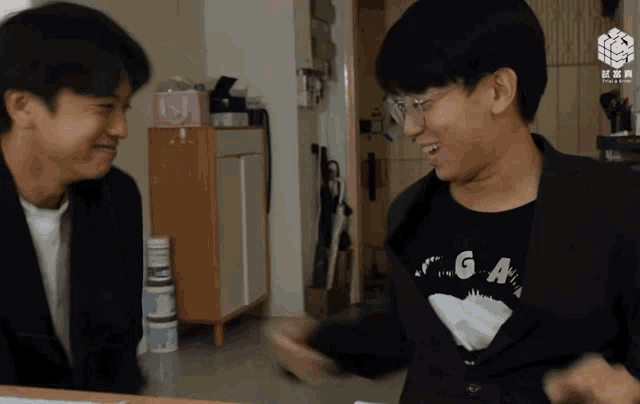 two young men are laughing and one has a shirt that says ga