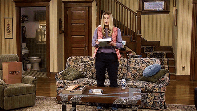 a woman standing in front of a couch holding a piece of paper with a deptos bag in the background