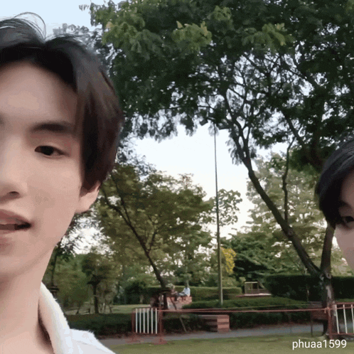 two young men are standing in a park with the name phuaa1599 on the bottom right corner