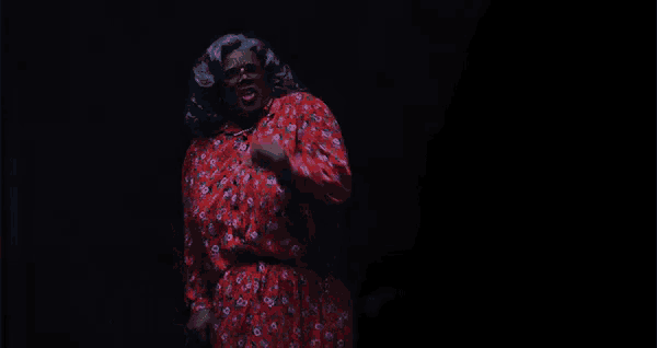 a woman in a red dress is singing into a microphone in a dark room .