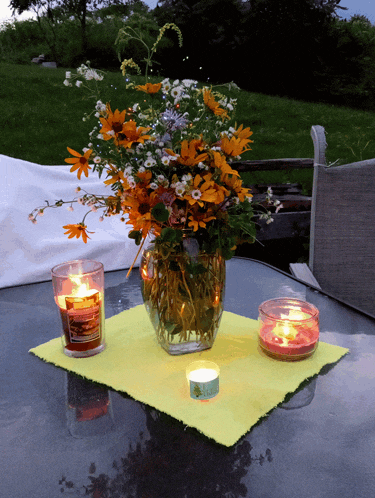 a vase of flowers sits on a table with candles