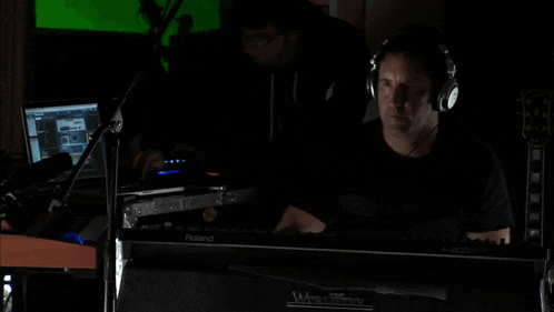 a man wearing headphones sits in front of a keyboard that says roland