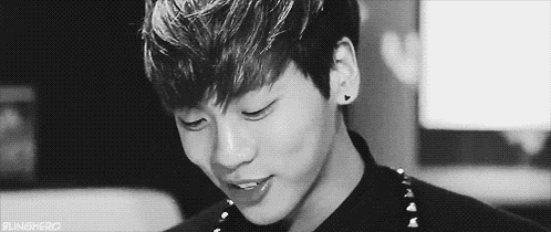 a black and white photo of a young man with his eyes closed and a smile on his face .