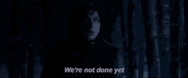 a man is standing in the dark with the words `` we 're not done yet '' written on the screen .