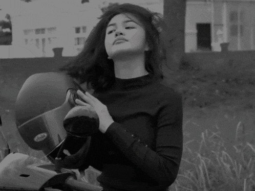 a black and white photo of a woman holding a helmet that says helmets on it