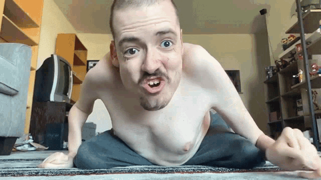 a man without a shirt is making a funny face while sitting on the floor