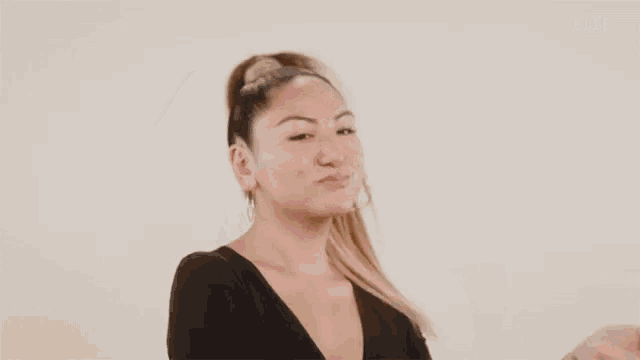 a woman in a black shirt is holding her hair in a ponytail .